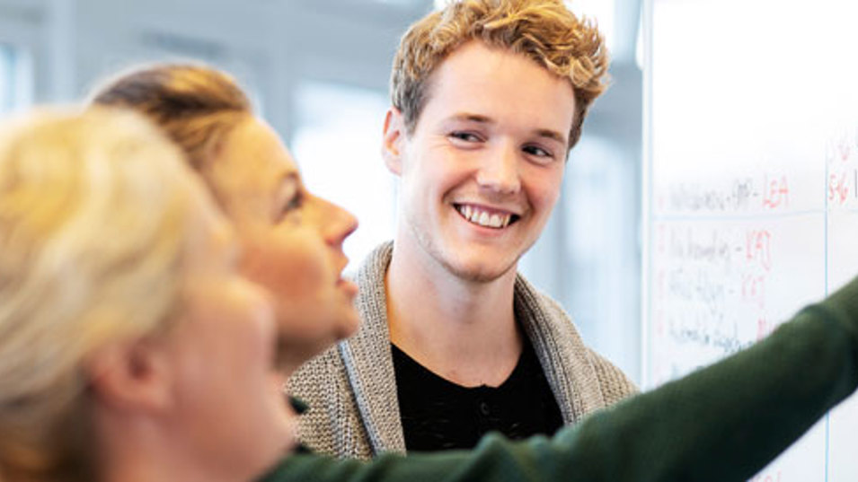 Tre kollegaer der taler og smiler til hinanden