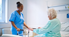 En sygeplejerske der hjælper en patient op at stå