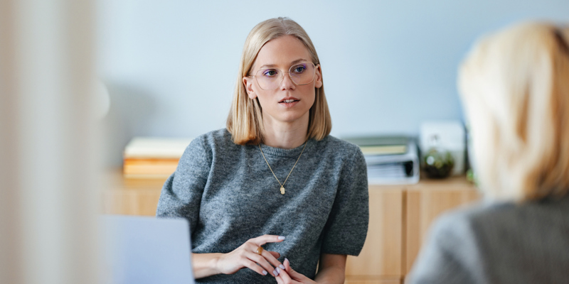 Kvinde sidder ved bord og taler med sin leder