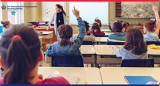 Skolebørn i klasselokale rækker fingrene i vejret