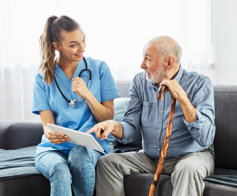 Hjemmehjælper snakker om medicin med ældre mand i eget hjem.