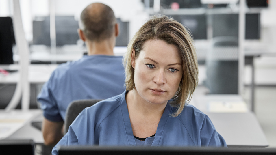 Kvindelig mellemleder på hospital kigger ind i computerskærm