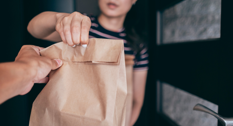 En kvinde der tager imod noget takeaway mad i døren