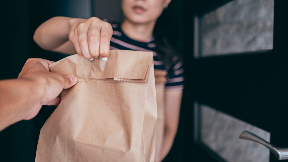 En kvinde der tager imod noget takeaway mad i døren