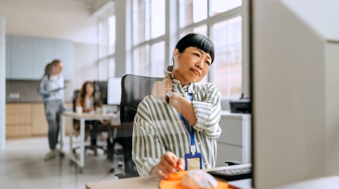 En kvinde der sidder på arbejdet og har ondt i nakken