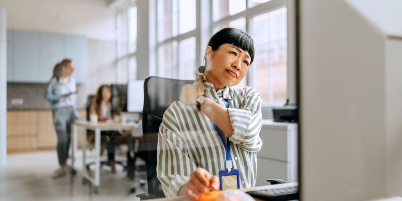 En kvinde der sidder på arbejdet og har ondt i nakken
